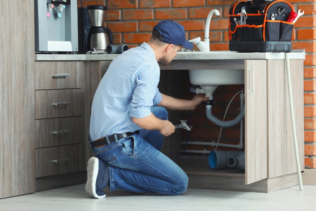 Plumber working under a sink
